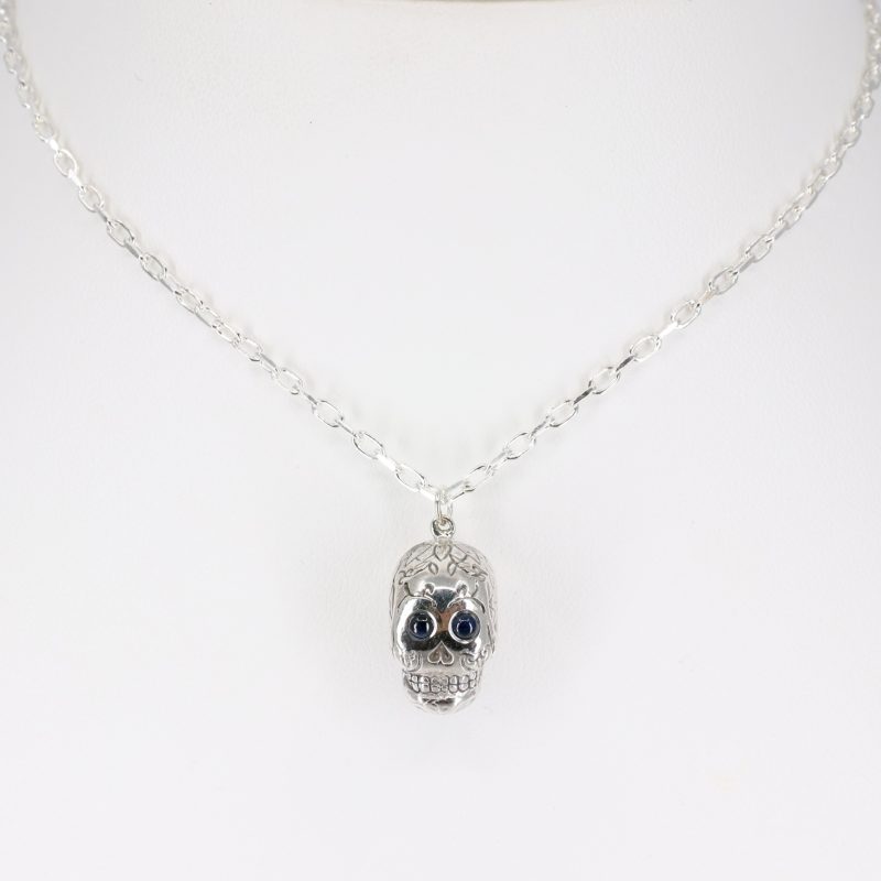 Silver sugar skull pendant set with blue sapphire eyes