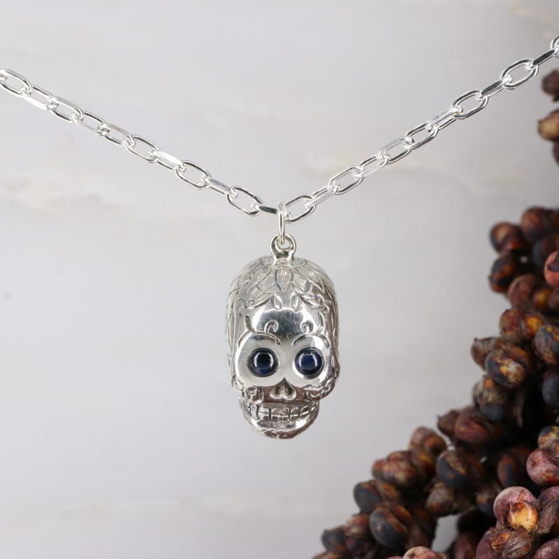 Silver sugar skull pendant set with blue sapphire eyes