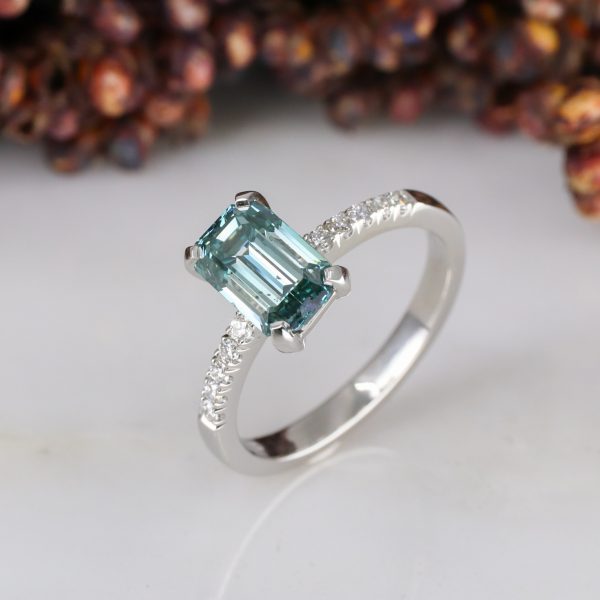 Platinum emerald cut blue diamond rise ring with white diamond shoulders