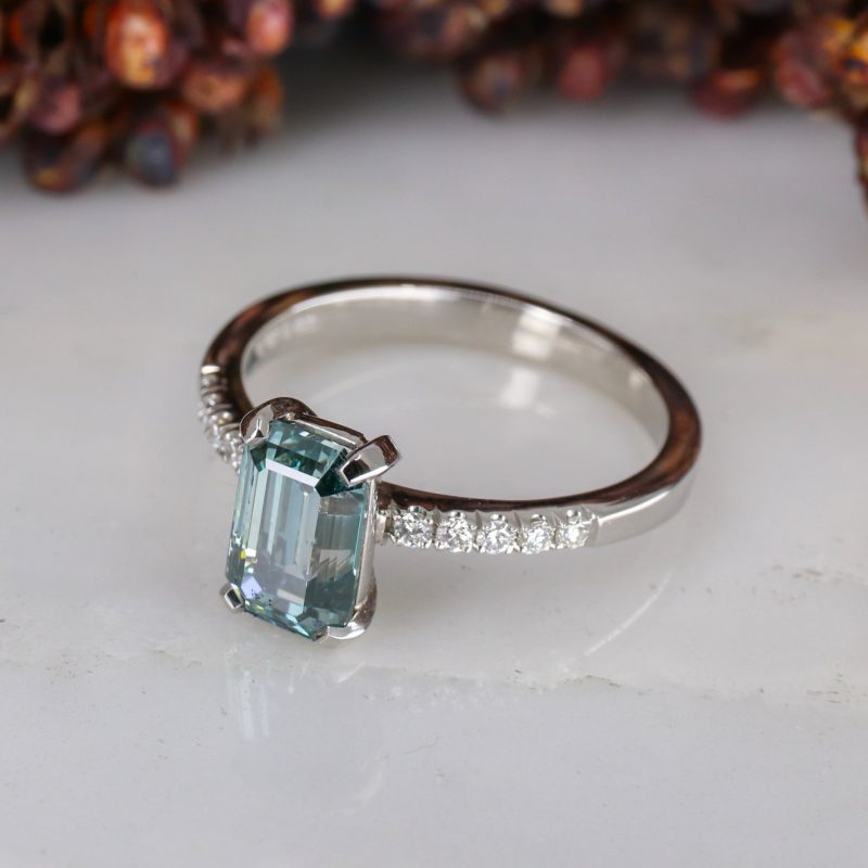 Platinum emerald cut blue diamond rise ring with white diamond shoulders