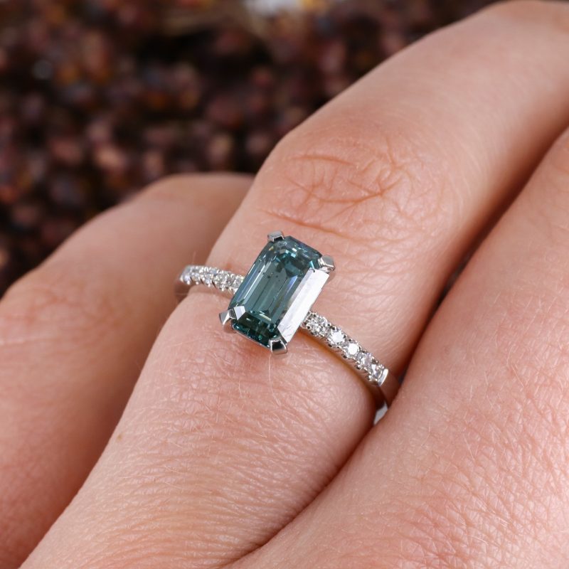 Platinum emerald cut blue diamond rise ring with white diamond shoulders